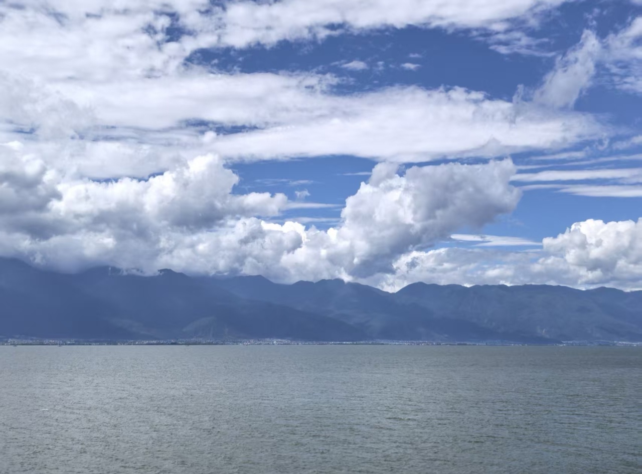 云南洱海，碧海连天，一望无际，天空白云连绵起伏，海岸两边被山峦围绕，云海相接形成