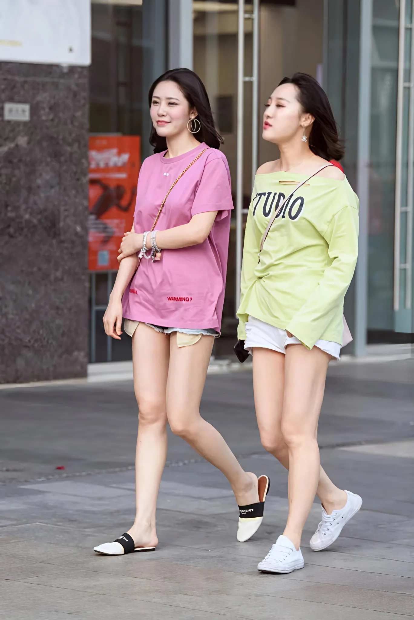 夏季穿搭:街头偶遇两位身穿大码T恤+热裤的靓丽美女，色彩鲜艳，引人注意