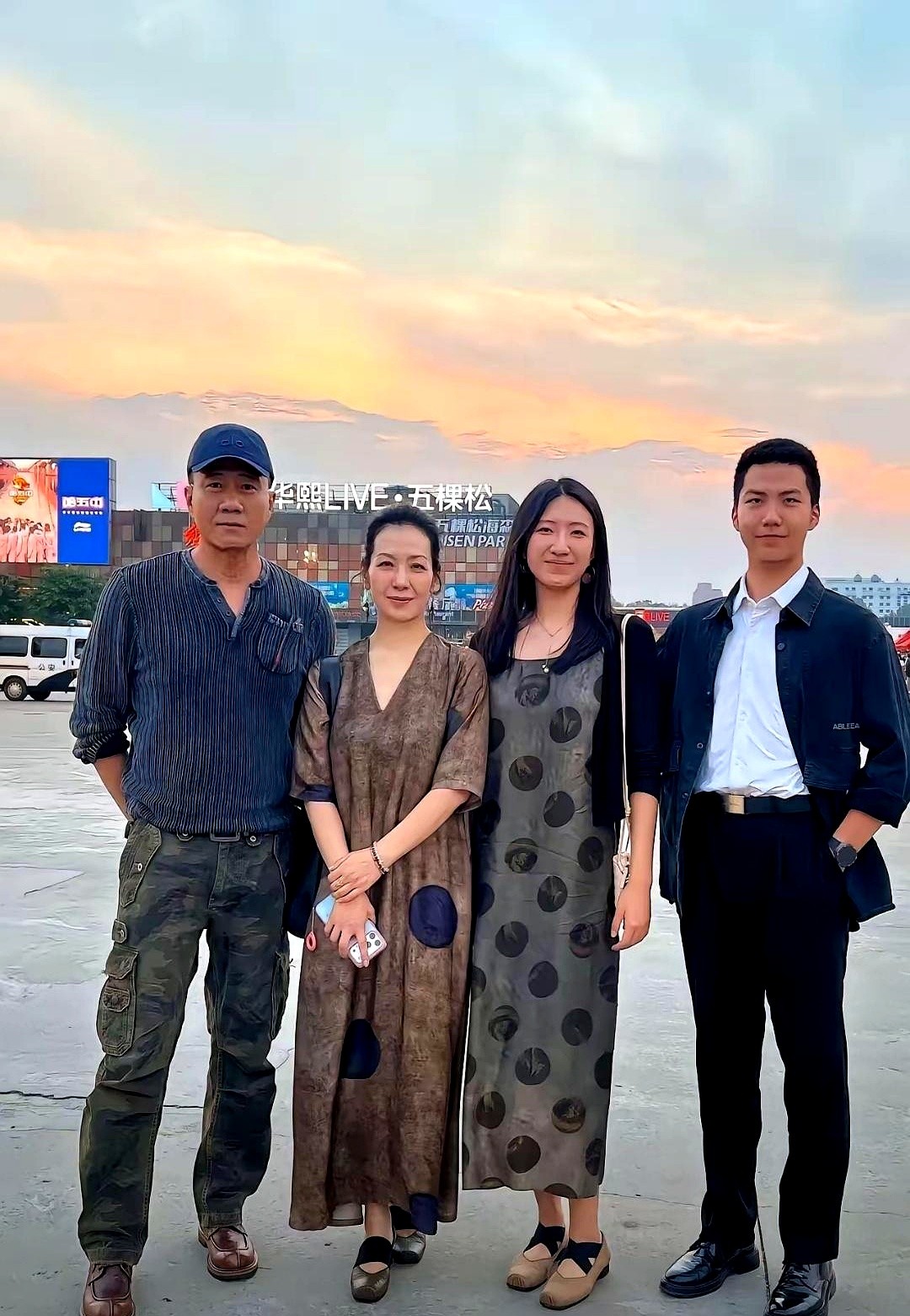 胡军一家四口在五棵松被拍到，这张照片信息量有点大。

夕阳下，胡军一身便服，没了荧幕上的硬汉劲儿，就是个普通中年男人。旁边是他老婆卢芳，穿了件香云纱长裙，那气质，一看就是话剧演员，安安静静地站着就很有分量。

最让人感慨的是俩孩子。女儿九儿都快比胡军高了，亭亭玉立。当年的“霸总”康康，现在胳膊比他爸