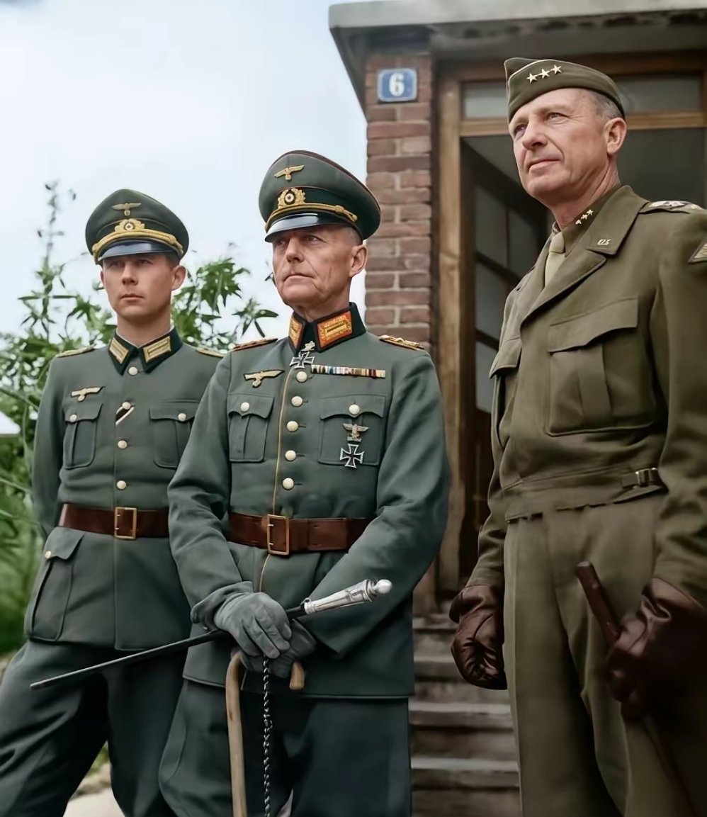 这是1945年西线德军总司令伦德施泰特被俘虏，即便当了俘虏，身上那股傲气也没丢，身穿干净整洁的军装，手里还拿着权杖，他的左边是儿子汉斯，同样一脸不屑。
​右边站着的是美军第七集团军司令亚历山大·帕奇，从中能看出两种军队的文化。 ​