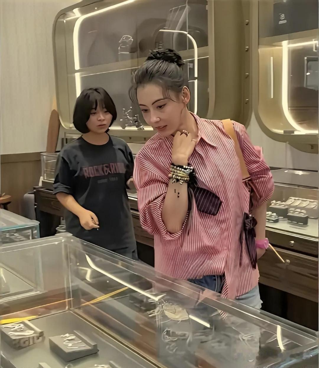 46岁张柏芝现身三亚周大福门店，穿粉色条纹衬衫搭破洞牛仔裤。她头发盘得很利落，皮肤又紧又有光泽，状态看起来超年轻！ ​