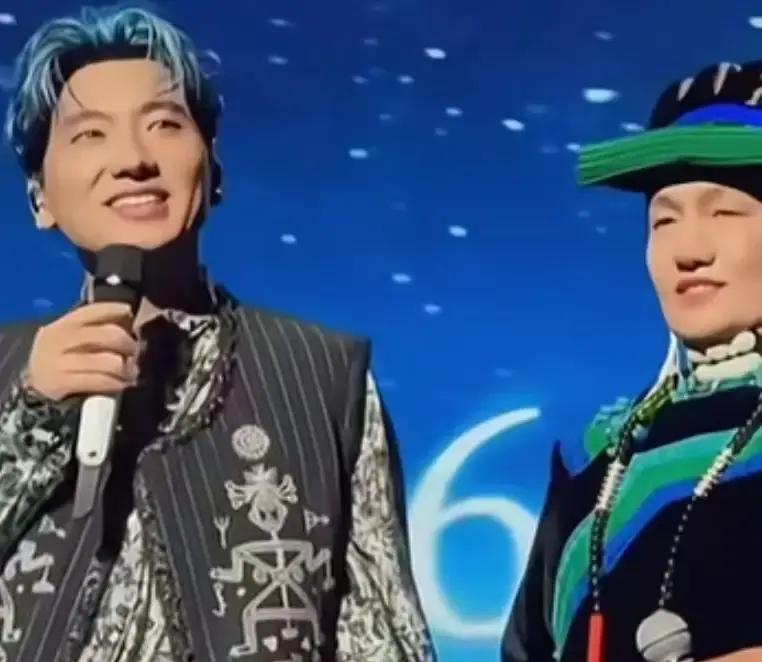 很多歌手在台上唱到动情处，顶多也就是给家里打个视频连线，或者对着空气隔空喊两声。
海来阿木倒好，直接把自己在大凉山的老母亲，稳稳牵上了几万人的大舞台。
老人家身上穿着整整齐齐的彝族传统盛装，满头银发配着精细的刺绣，一脸慈祥。
上了台一点都不慌乱，全程笑眯眯地冲着台下观众用力挥手。
其实稍微细