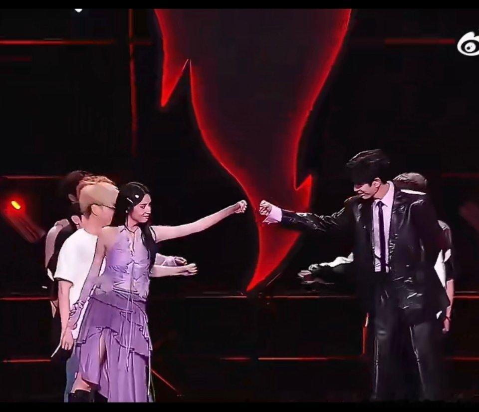#张凌赫周也碰拳#
无畏契约成都表演赛上，张凌赫和周也赛前先来了一个抬手碰拳。
张凌赫一身黑皮西装清冷帅气，周也一袭紫色礼服灵动飒爽，电竞舞台氛围感拉满。没有刻意营业的暧昧感，就是选手之间坦荡大方的互相打气，简单一个碰拳动作，俊男美女的适配度直接拉满。
两人颜值气质高度契合，同框画面 ​