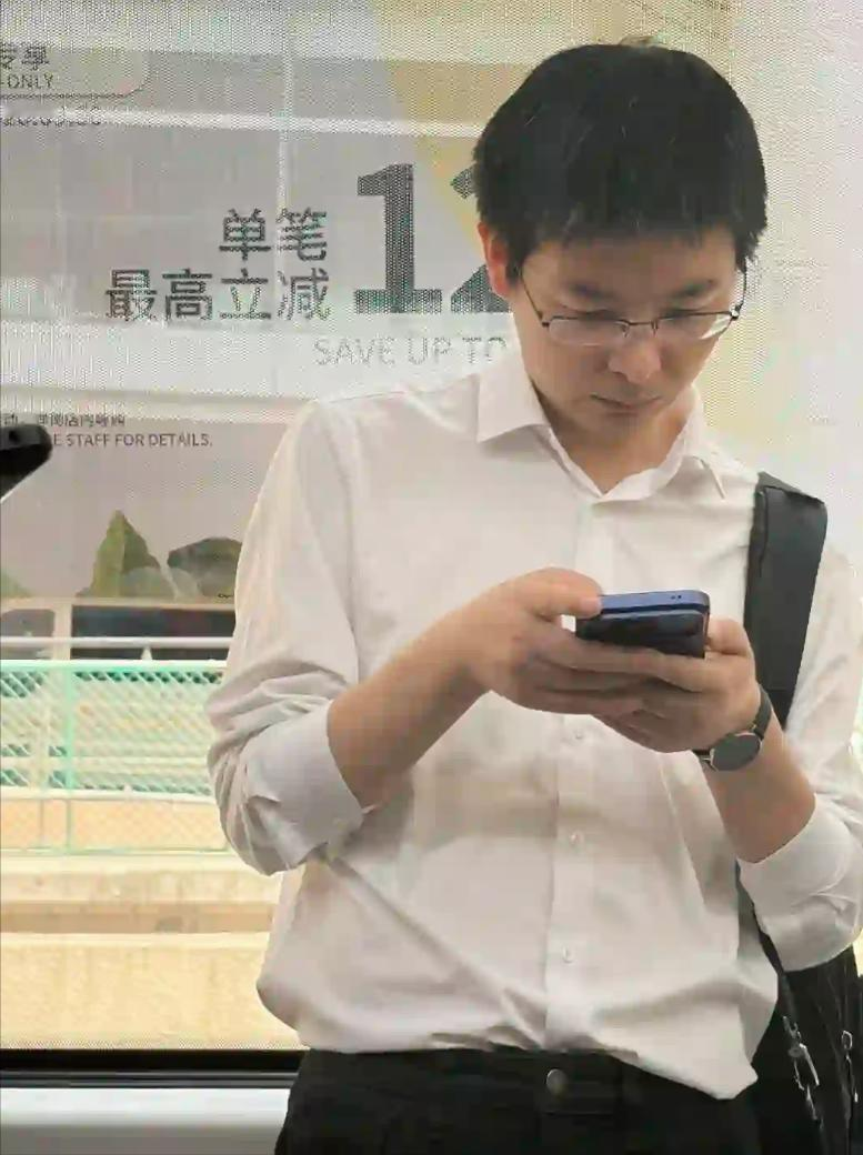 36 岁宇树科技总裁王兴兴在北京机场坐摆渡车被偶遇。

就一件简单白衬衫，背着双肩包，没有随从助理，一个人低头盯着手机，神态看着有点疲惫，能看到头发里夹杂不少白发。

很难想象，这就是刚上市不久的宇树科技创始人。之前春晚机器人亮相，全网热度拉满，那时候全是他意气风发的报道。可上市之后资本市场变化很现