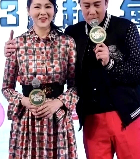 蔡国庆的手轻轻虚掩在伊能静的胳膊上，这个下意识的动作根本装不出来。

台上递过来话筒，蔡国庆自然地接下话茬，转身面对镜头，手顺势搭在身旁伊能静的臂弯处，护着她往前站。

其实这俩人同岁。当时伊能静刚生完孩子没多久，身材还没完全消肿，站在聚光灯下多少有点局促。蔡国庆不仅全程帮忙挡话，这一个小小的肢体细