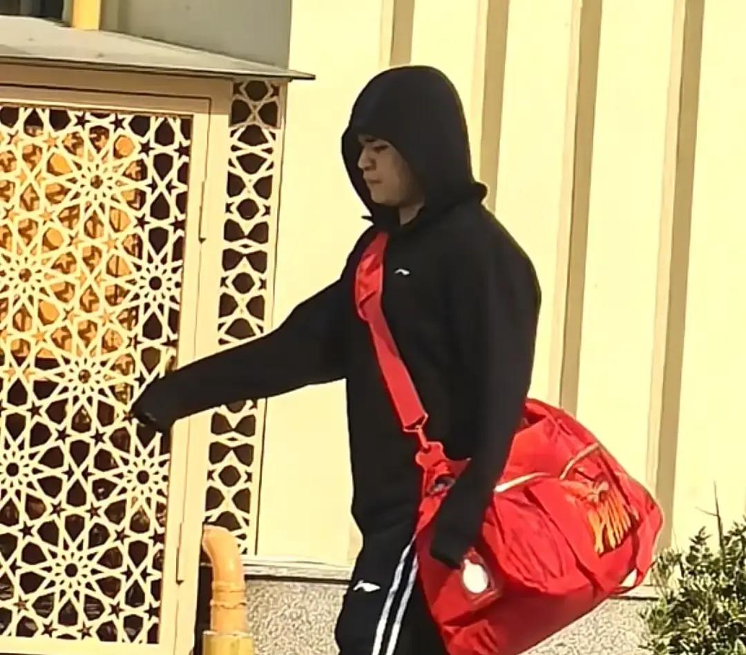 连轴转了小半年的林诗栋，这次面对身上的伤病，终于被迫按下了减速键。
以往在赛场上总是风风火火的十九岁小将，去训练馆的路上，破天荒换了一整套纯黑行头。黑色卫衣配黑色长裤，连帽子都严严实实扣在头上，整个人显得格外低调，唯独肩上那个大红色的国家队训练包扎眼得很。
步子迈得慢吞吞的，看得出身体确实是在咬