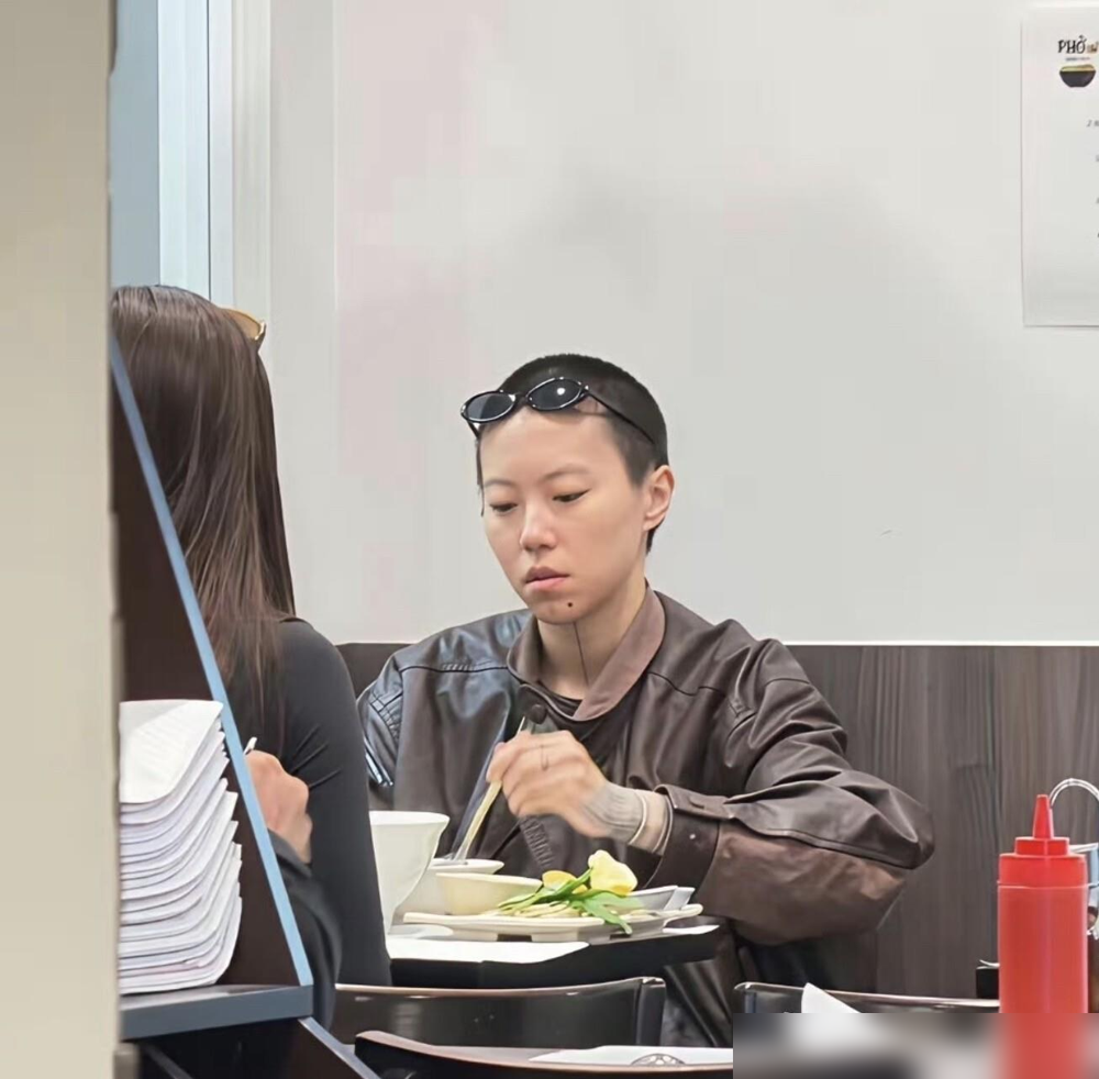 窦靖童蹲巴黎路边吃汤面，头发乱糟糟的，吸溜得那叫一个香。镜头怼脸拍，她眼皮都没抬。
早些年她可不这样。剃头、纹身、中性打扮，浑身绷着股劲儿，急着跟王菲女儿四个字划清界限。结果越使劲，标签贴得越牢。
现在倒好，直接摆烂式松弛。采访里她自己说的，跟王菲一次架都没吵过，14岁说不想上学，王菲就一句想清