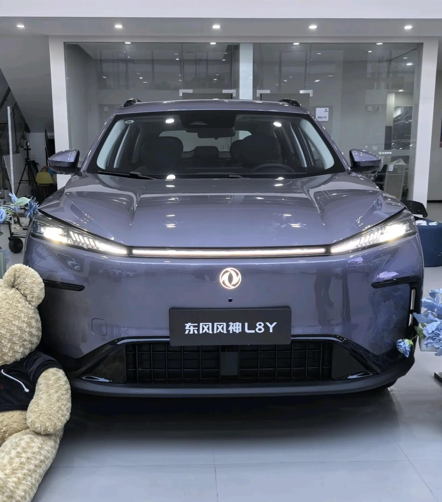 到店体验东风风神L8Y：坐进车内，才懂双C位的分量
九万级纯电SUV能把车内做成什么样，翻配置表给不出答案。这次在门店把重点放在静态乘坐和座舱体验上，前后排逐一坐了一遍。
展厅这台琉璃紫展车的漆面在灯光下透着光泽，封闭式前脸、贯穿灯带和可点亮的双飞燕标识衔接干净，侧面溜背线条利落，外拉式门环握感顺手