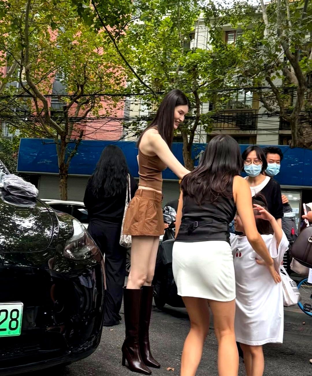超模到底有多压人？看何穗这组街头生图就懂了。

她一身棕色套装踩着高跟长靴，往人群中间一站，直接形成断层身高差，轻轻松松“俯瞰全场”。身边路人跟她一对比，画面反差感瞬间拉满，一眼看过去简直像大人不小心走进了小朋友的圈子。

普通人跟超模同框，真就只能当背景板吗？