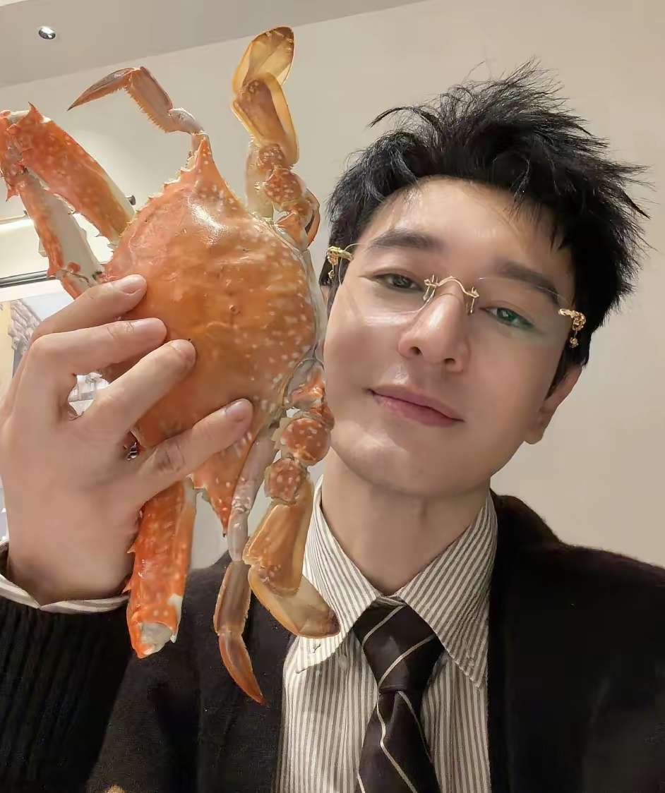 黄晓明，高调发文！9月20号下午，黄晓明在个人社交平台上高调发文，还配了两张照片，引发网友热议。第一张照片是黄晓明自己举着只肥硕的大梭子蟹自拍，螃蟹张牙舞爪的，他本人倒是笑得挺淡定。

仔细看黄晓明那身打扮，跟手里那只螃蟹的反差感简直拉满。

条纹衬衫配领带，外面套了件深色毛衣开衫，脸上架着副无框金