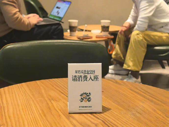 【#星巴克消费入座首日探访#：提示牌上桌，现场以柔性引导为主】#星巴克店员称会友好提醒未点单顾客# 10月22日是星巴克施行“消费入座”的首日。星巴克中国此前确认，自今日起在全国门店开始施行“消费入座”，门店将摆放相关提示牌，并发布《第三空间倡议》，倡导顾客合理使用座位、控制交谈音量、避 ​
