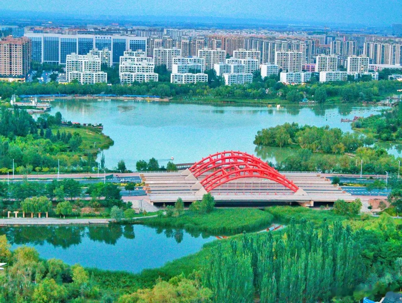 在兰州新区安家 在新区住久了，会发现这里的“水”不只是风景。文曲湖、栖霞湖，湖面开阔，风一吹波光粼粼。每年5到11月的周末夜晚，音乐喷泉准时赴约，水柱随旋律起舞，大人牵着孩子，老人摇着扇子，安安静静看水跳舞——这是新区人最熟悉的夏夜。但水的故事不止于此。湿地公园里，水草丰茂，候鸟南来北往，成群的水鸟在浅滩觅食、盘旋。水阜河滋养着两岸的生态，也养出了这片土地的灵气。海豚公园、百花公园的水边，是孩子们的乐园，夏天踩水打水仗，那些清凉的欢笑，是童年最深的记忆。喷泉是水在表演，湿地是水在呼吸，候鸟是水在招呼远方的客人，孩子们的嬉闹是水在唱歌。有水的地方，日子就有了呼吸。在这里读懂兰州新区