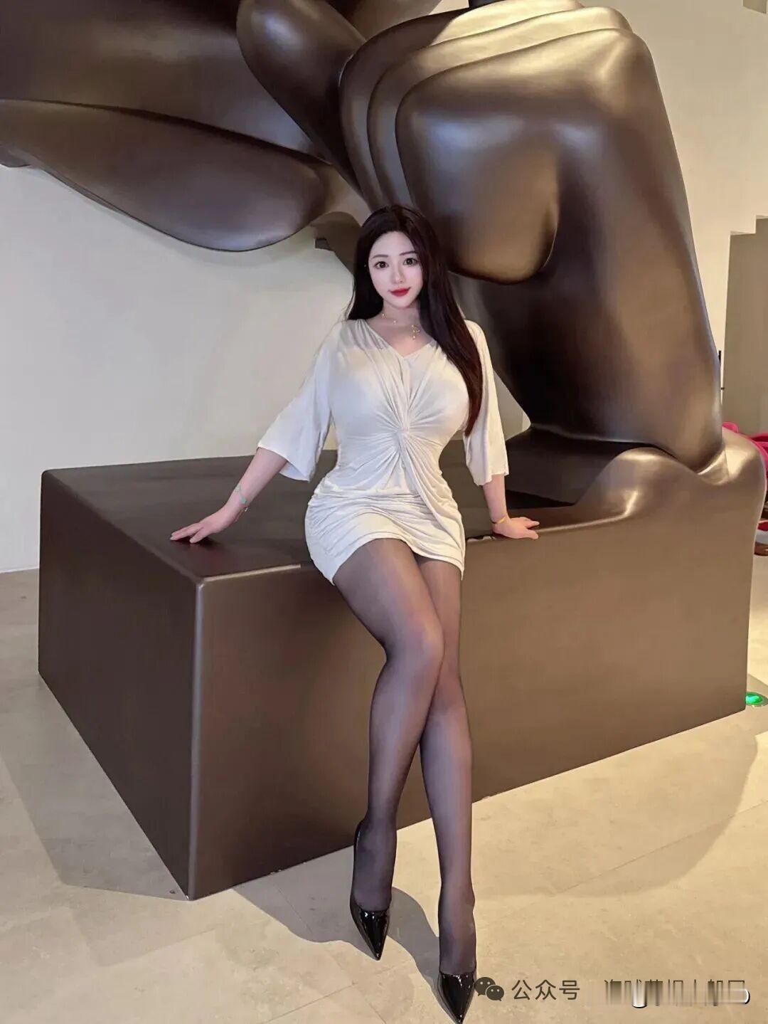 想象一下，一袭优雅白裙的佳人，静静地坐在现代艺术雕塑旁，那画面简直美得...