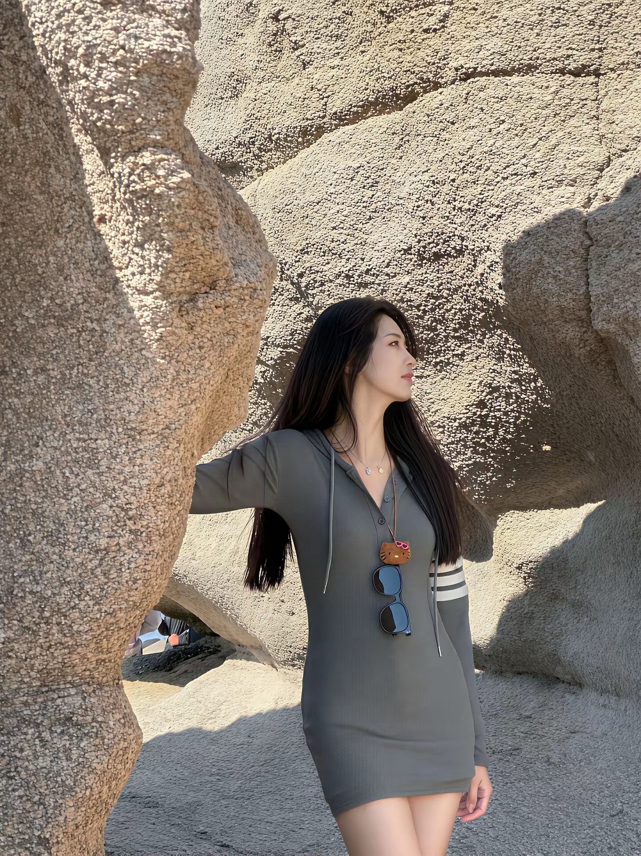 阳光下的时尚女孩，自信地倚靠在岩石上，展现自然与时尚的完美结合。