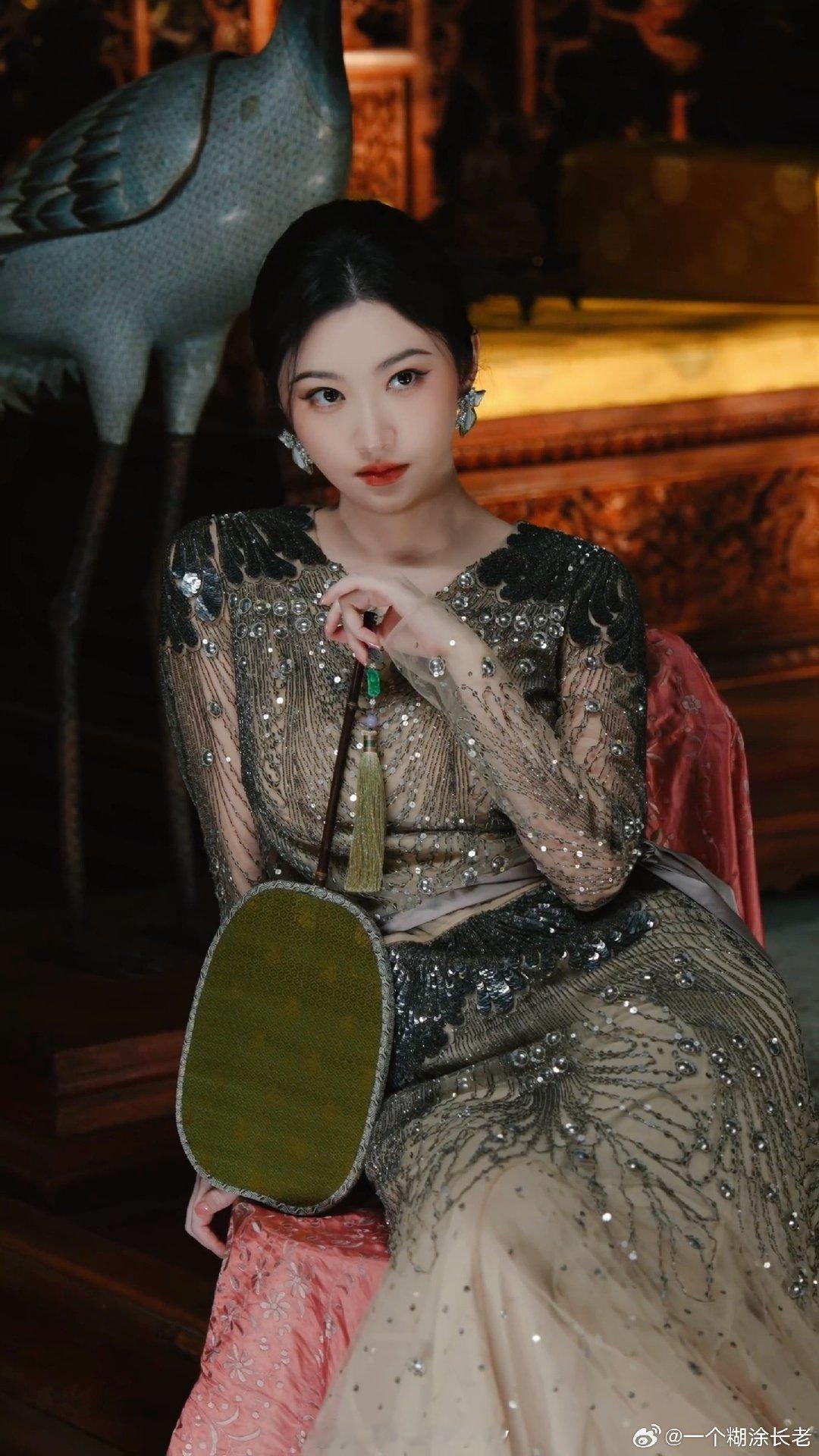 #景甜[超话]# 
光影交错间，复古的底色将氛围感拉满。繁复的珠绣长裙与手中那把绿扇相得益彰，耳畔微光点缀，不张扬，却足够沉稳。眼神里的从容和笃定，透着一份岁月洗礼后的中式雅致。安静地坐在那里，便是旧时光里走出来的温润与贵气。✨
#景甜红墙古刹大片##景甜# ​