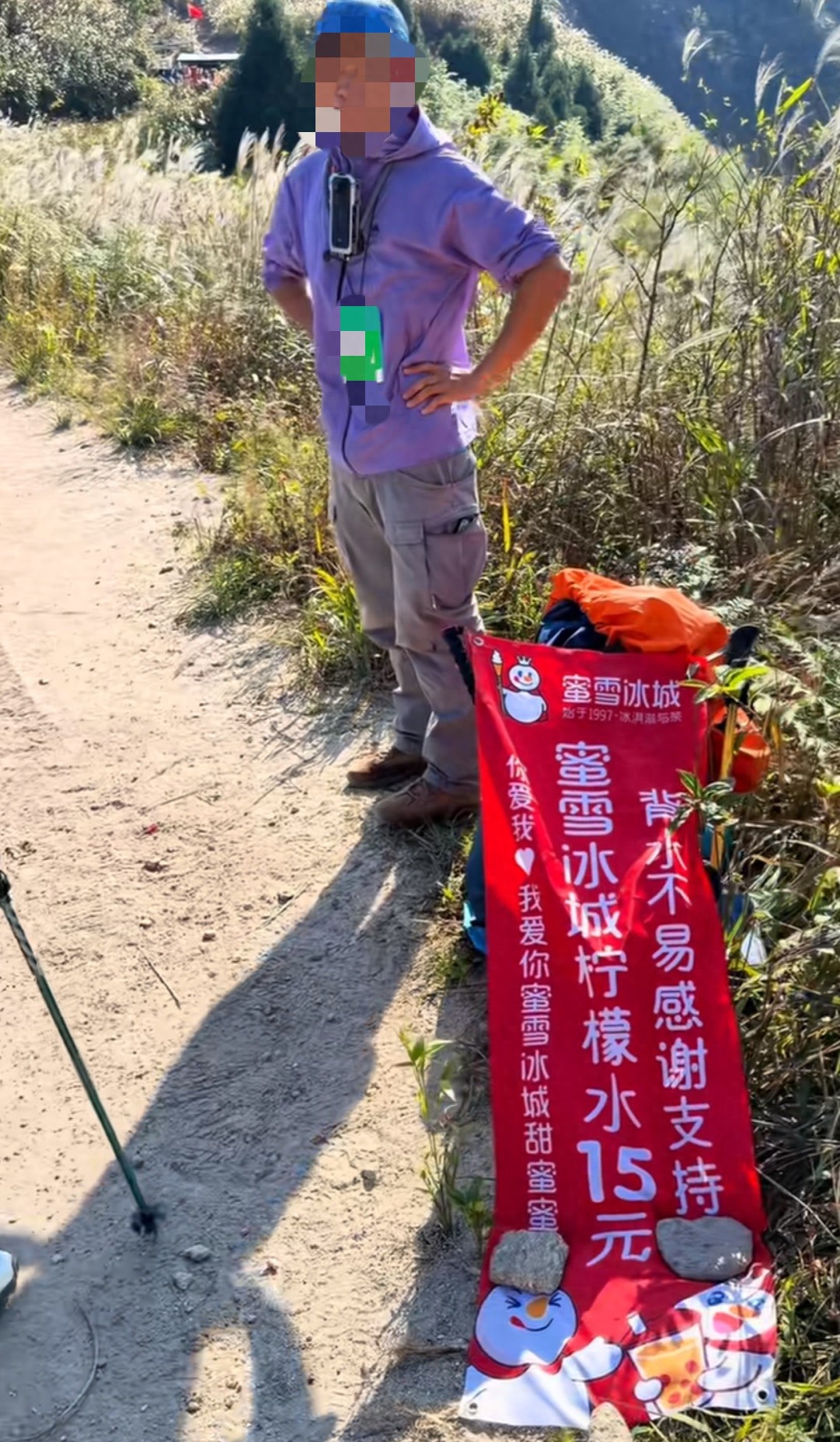 “背水不易感谢支持”，横幅旁标着柠檬水每杯15元。据极目新闻报道，这是江西萍乡武功山上一名男子卖蜜雪冰城柠檬水时打出的招牌。最值得琢磨的，是他把“背水”也摆到了价格前面。

我认为，搬运的辛苦当然该算钱。山顶没有这家品牌的门店，把饮料送到山上，本身就是劳动。但15元是售价，不是净赚，不能看见卖得贵就