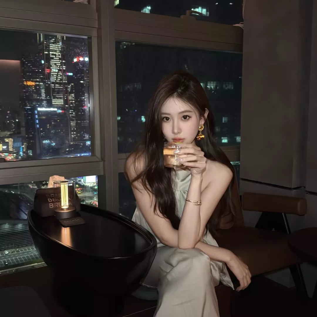 都市夜景中的优雅女性，啜饮香槟，享受静谧时光。