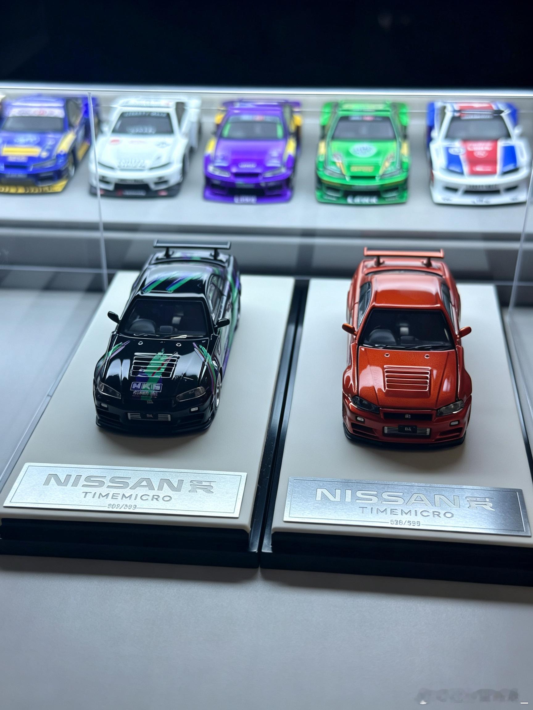 TimeMicro 1:64 日产GT-R R34 HKS涂装仿真合金车模
主题涂装：车身采用经典HKS改装品牌主题拉花，搭配机盖细节刻画、大尺寸尾翼，还原了日系JDM改装文化的标志性风格。
前景R34模型：采用金属橙红珠光漆面，还原了原厂经典的多辐式轮毂、标志性的双层尾翼和车尾四出排气，搭配带铭牌的皮质展示底座。 ​