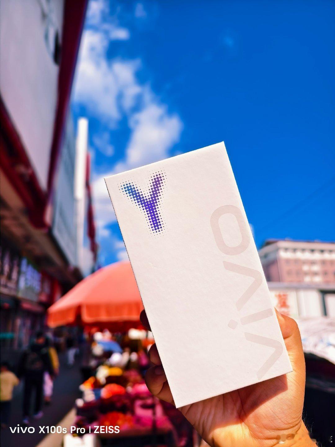#vivo[超话]# 迎着晴朗蓝天，在热闹市井街头开箱新机。白盒简约精致，身后是人间烟火，用全新vivo，记录生活里每一份鲜活与美好瞬间。#vivo超话# ​