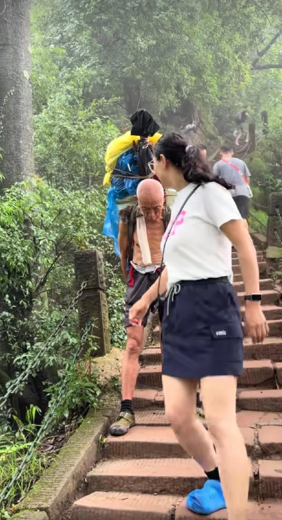 成都青城山的石级山道上，游客络绎不绝。一名年轻女子下山时，遇见一位白发背山工老人。老人光着上身，背着装满行包的背篓——这些都是爬山游客累了托付他背到山脚的。烈日下，汗水不断滴落，他走不了多远就得用木杵撑住背篓歇脚。女子经过时，老人正歇息。她眼里满是心疼，停下脚步，从包里掏出一瓶水，拧开瓶盖，递到老人手中。老人喝了水，她又接过瓶子拧好盖，轻轻放在背篓里，才转身离开。下山路上，她不时回头，眼神复杂。石道不语，有人登山游玩，有人为生活负重前行。老人本可安享晚年，却仍靠体力挣一份辛苦钱，背篓里扛着的是家的责任。那瓶水，是女子对劳动者最温暖的尊重，也是对所有努力生活的人最真诚的致敬。每个人都有自己的背负，命运不同，责任相似。这一瞥、一瓶水、一个回望，让人看见艰辛中的坚韧，也看见平凡里的善意。生活不易，但温暖常在。愿每一份负重都被看见，每一滴汗水都被温柔以待。中国正能量正能量