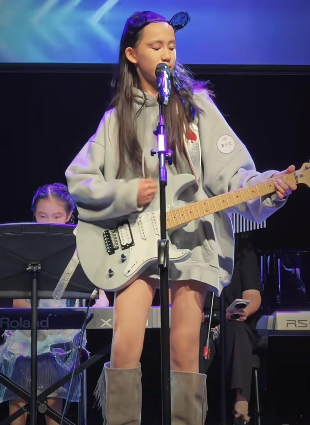 黄磊二女儿登台演出，12岁黄少艾穿长靴，披着长头发，手弹电吉他，又飒又酷，一家子文艺范，却养出来一位“摇滚风”，妹妹比姐姐黄多多小时候要洒脱活泼很多，老二很明显是喜欢玩音乐的类型，看起来就很有个性。
孙莉晒出孩子参加活动的现场动态，她也为女儿感到骄傲，大女儿多多已经去纽约读大学了，二女儿成了家里的主