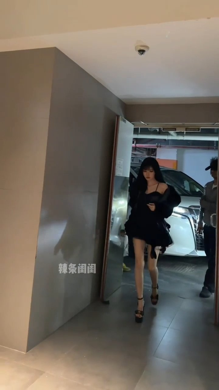 镜头视角的偏差，往往会催生出两种截然不同的观感...
 
今日鞠婧祎拍摄《万花世界》最新片场路透流出。一身黑色碎瓣吊带短裙搭配毛绒皮草外套，黑长卷发配上墨镜，冷感又带着浓烈的富家千金气场，精修镜头之下身段比例格外抓人。

 但此前脱离精修的路人随手拍摄画面，却呈现出另一套视觉效果。不同机 ​