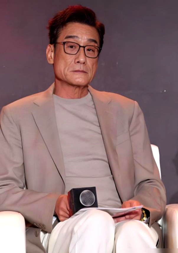 铜锣湾街头，一个穿破背心斜挎旧帆布袋的老头正举着手机找角度。

路人凑近一看，这不是演黑老大的梁家辉吗。68岁没保镖没助理，脸上的老人斑和深褶子全亮在太阳底下。有人凑上去求合影，他一把接过手机找光线，拍完还弯腰给人家道谢。

当年摆地摊熬过低谷，如今双胞胎女儿出嫁自己当了外公。荧幕里再狠狠，下了戏也