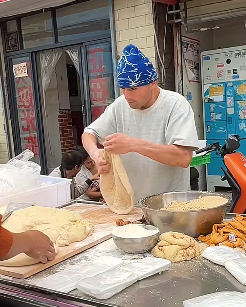 最近西安街头这个新疆烤馕摊真的火得离谱，摊主阿达西在这边摆了整整4年，之前都是周边老客常光顾，这阵子突然就火到全城都有人专程找过来排队。
他家馕最绝的是定价，原味的才卖3块，夹了核桃仁、葡萄干的豪华款也才5块，比很多商圈里卖十几块的馕实在太多。刚出炉的馕外皮脆得掉渣，内里软乎乎的带着麦香，咬开夹馅款