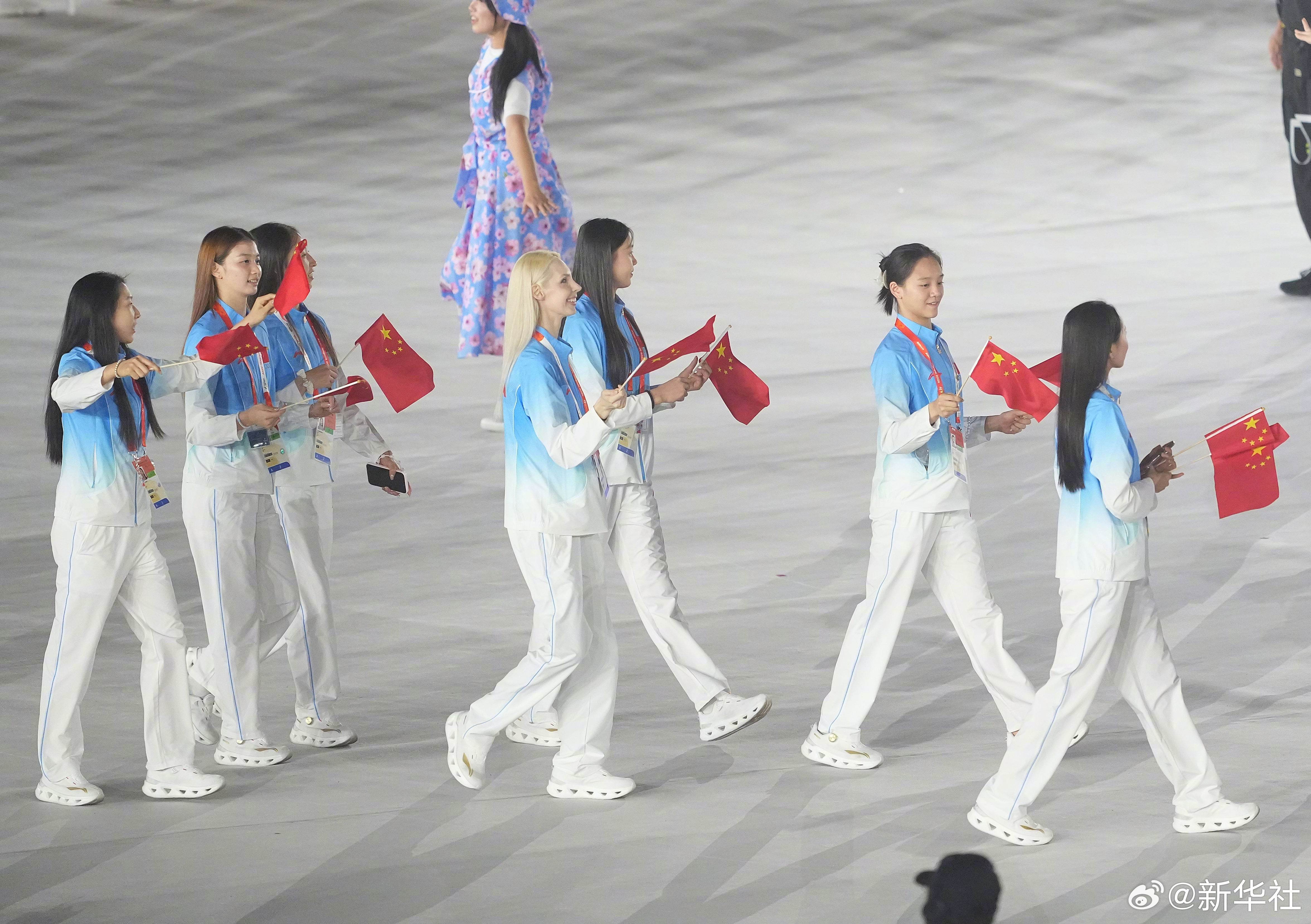 中国代表团亚运闭幕式亮相，我是从后台通道那条视频里看到的。

正式入场前，队员在通道里候着，两排，前面的人手搭着前面，像小时候排队进操场。有个个子高的在低头理腰带，旁边一个女孩伸手帮他把衣服下摆扯平。没人说话，都在等前面那扇门开。

门一开，旗手先出去，后面跟着走。

我特意倒回看了两 ​