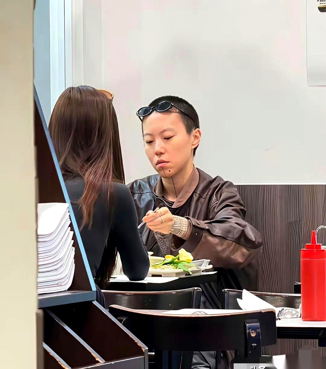 窦靖童正跟一个背影神似宋妍霏的女生同吃一碗河粉。
她细心地把面条挑给对面的女孩，又毫不客气地把人家那头的丸子全划拉到了自己碗里。
网友发现她下巴上那个虾线纹身并没有彻底洗干净，而她跟王传君在2023年合作拍的那部剧刚好拖到现在才放出来。
看这俩人无时无刻不腻在一起的架势，窦靖童在那女生身边确实显得荷